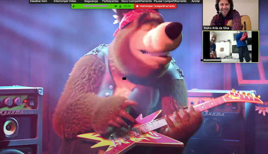 A screenshot of a video call showing an animated bear playing a guitar, with a small inset showing a man with hearing assistance smiling and watching.