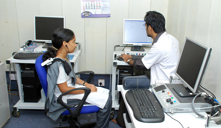 A family doctor conducting a cardiovascular test on a female patient in a medical office, using advanced diagnostic equipment.