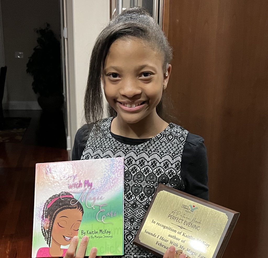 A girl smiling at the camera, holding a book and a certificate, surrounded by her family.