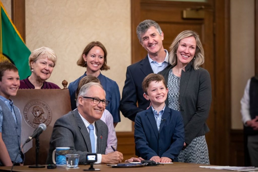 Boy smiles with governor on signing a bill into law