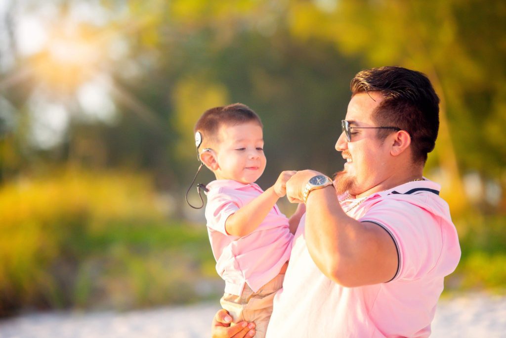 father holding small son with cochlear implant