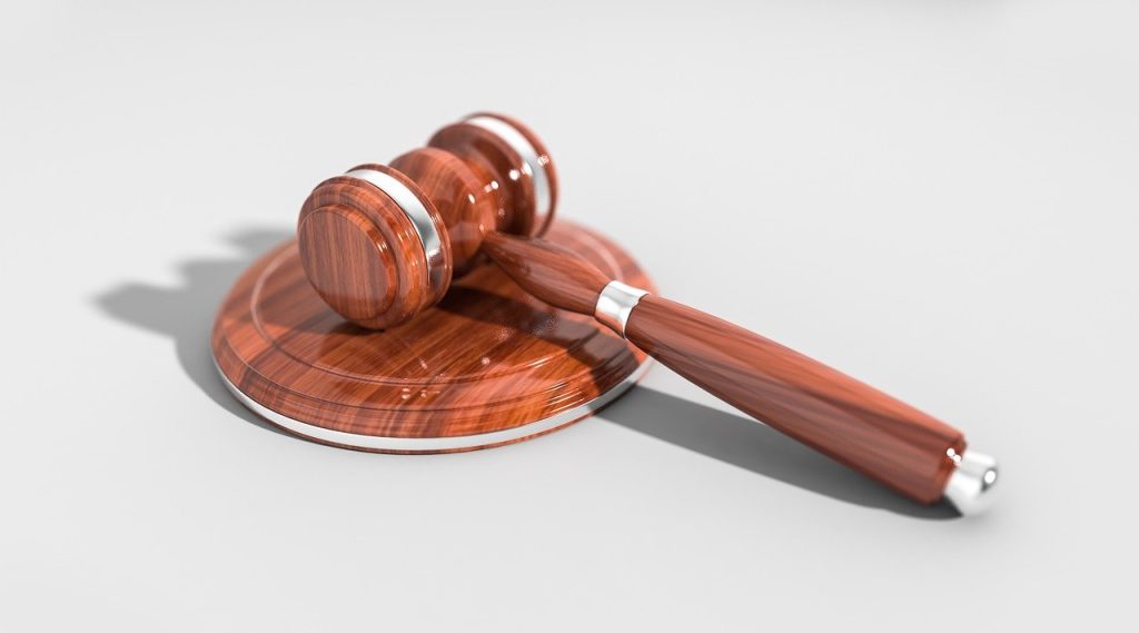 A wooden judge's gavel and sound block on a white background, used to hear cases in court.