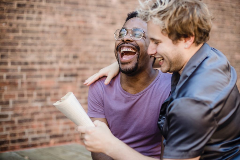 Two family members laughing and sharing a moment together while one holds a rolled-up paper.