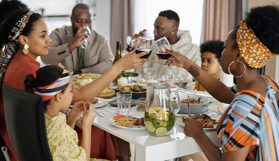 Family enjoying a meal together while two adults toast with glasses of wine as their child listens intently.