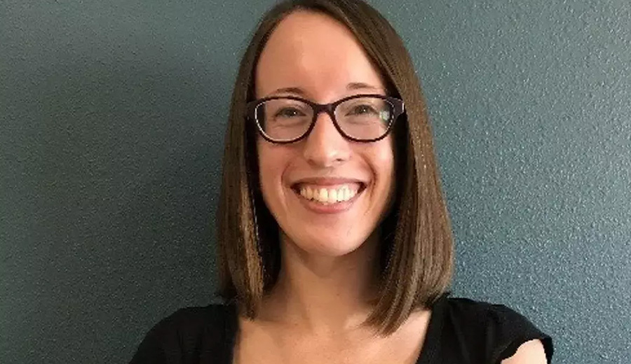 A smiling woman with short brown hair, wearing glasses and a black top against a teal background, offering family assistance.