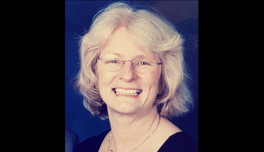 Portrait of a smiling elderly woman with glasses, wearing a black top against a blue background, using hearing aids to better hear her family.